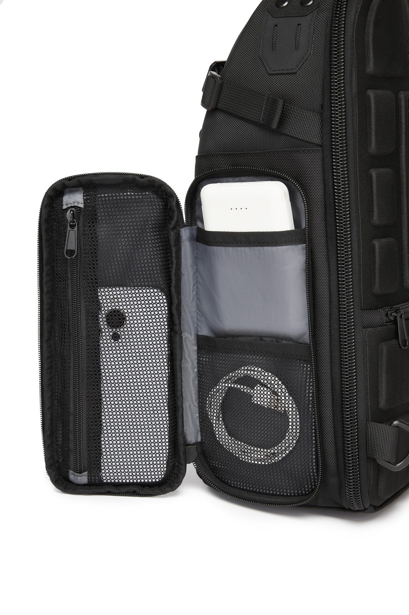 Ridge Sling Backpack 12L in Black - close-up of the front organizer pocket with mesh sleeves holding a phone and power bank