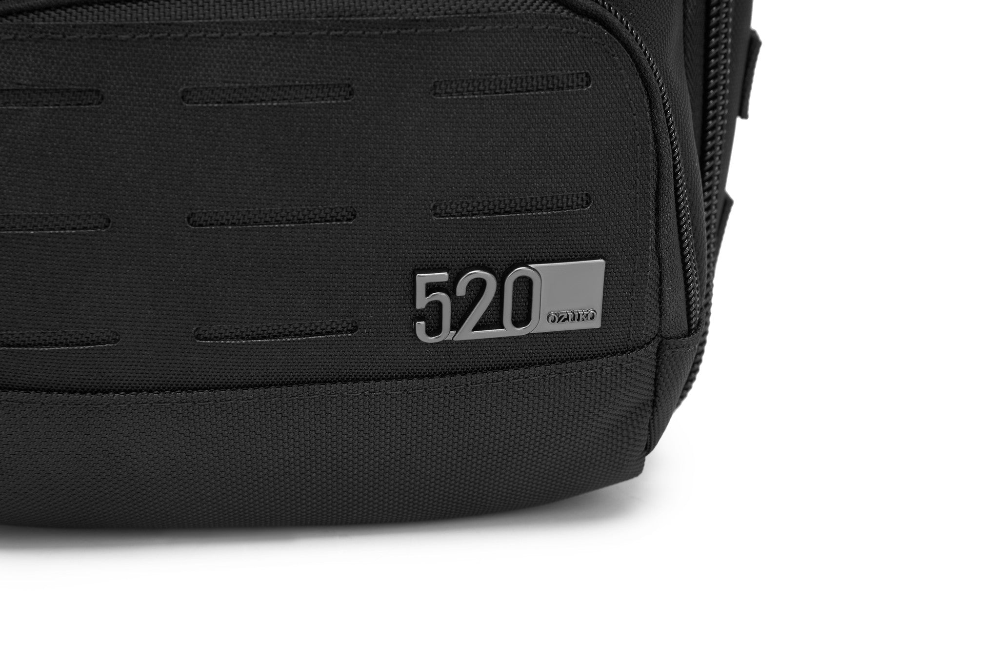 Daytrip Backpack 12L in Black - close-up of the metal 520 by OZUKO brand tag on the lower panel