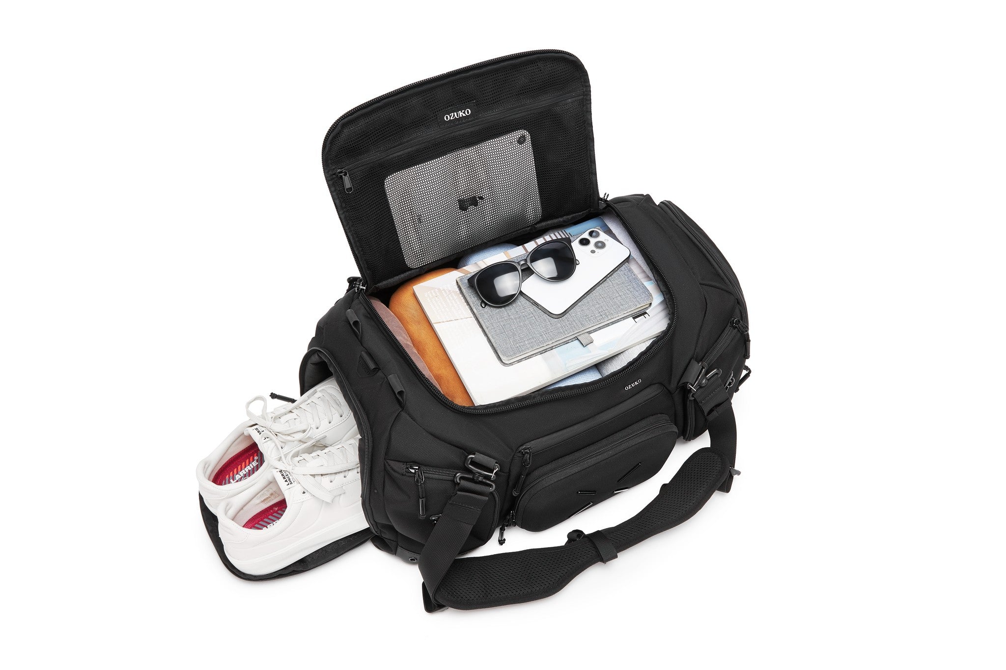 Black Voyager Duffel 40L interior lid pocket packed with white sneakers, a notebook, sunglasses, and a phone