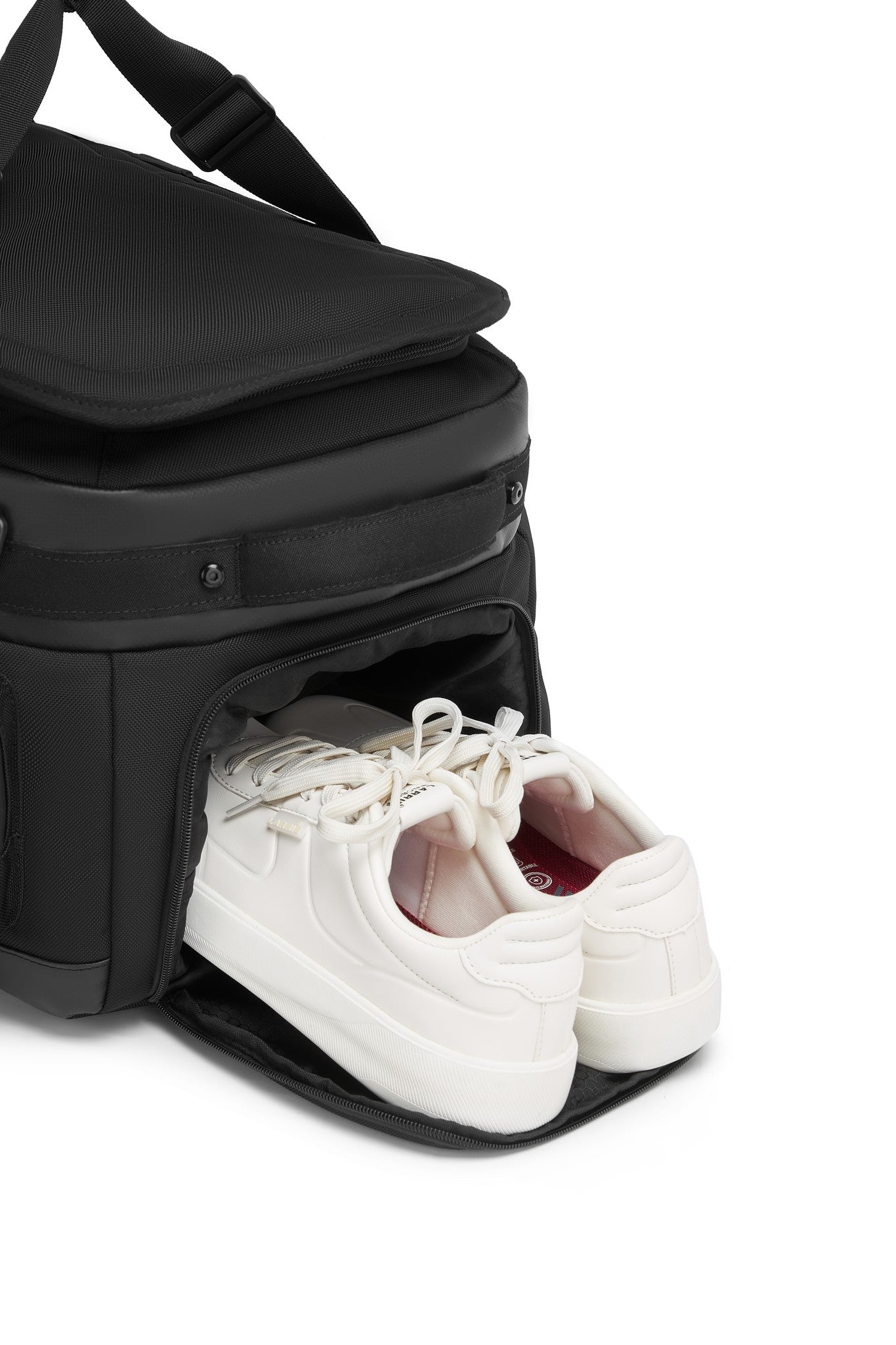 Close-up of the Oono Voyager Duffel 50L's bottom shoe compartment with a water-resistant lining, holding a pair of white sneakers