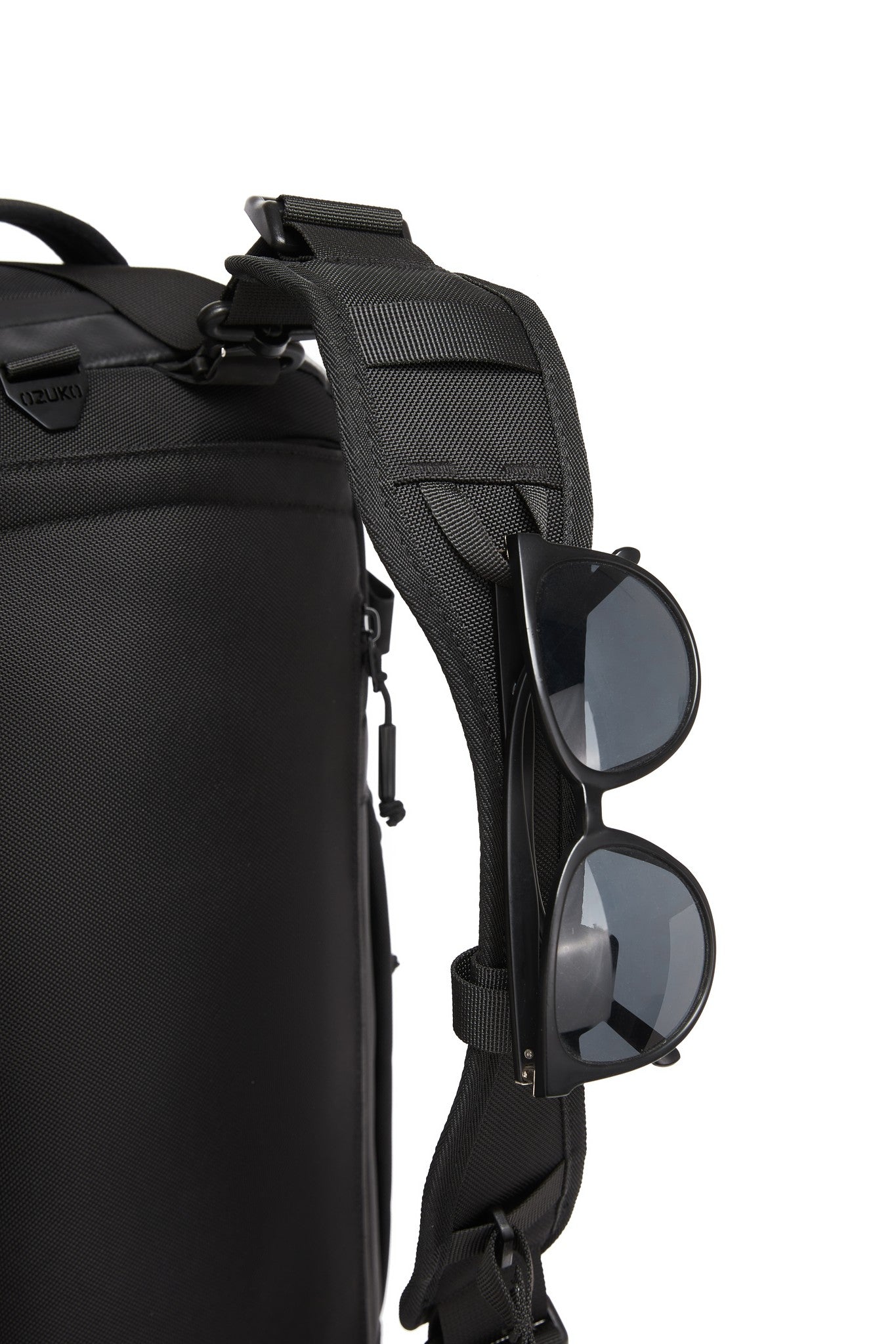 Close-up of sunglasses hooked onto the adjustable shoulder strap attachment loop