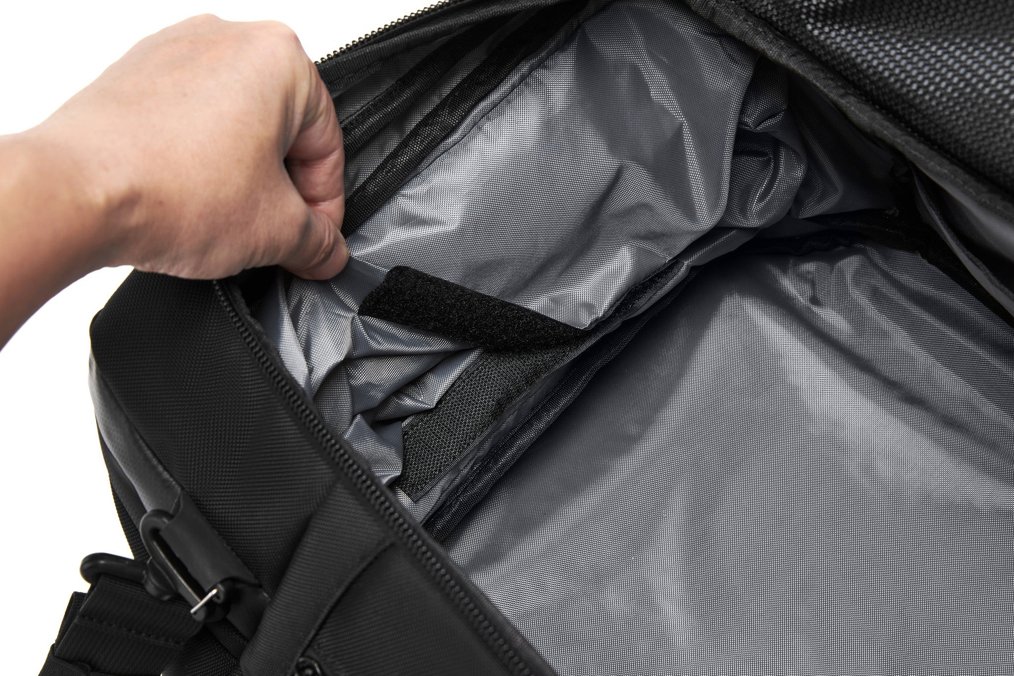 Close-up of a hand lifting the velcro-secured mesh document pocket inside the main compartment